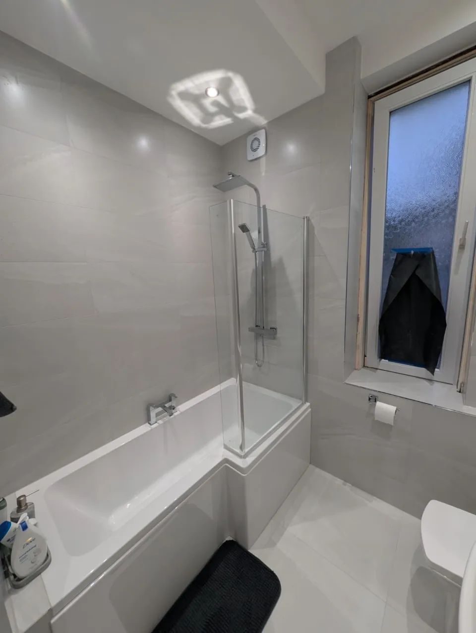 White fitted bath and shower screen with grey walls