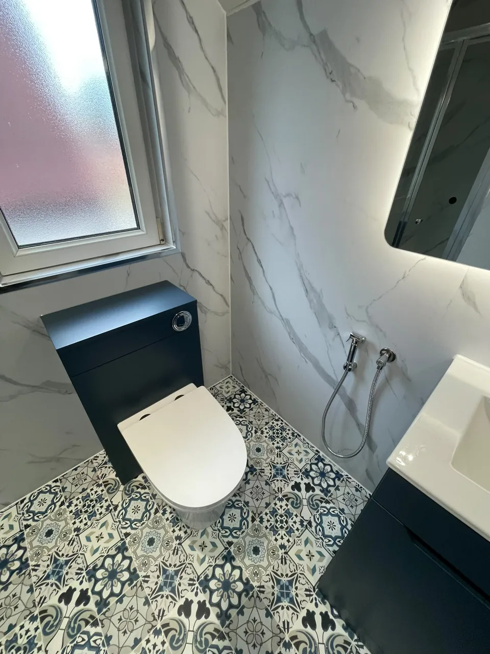 White toilet with navy unit and patterned floor