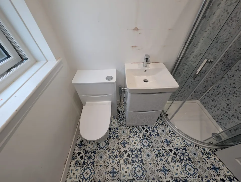 Compact shower room with white vanity and patterned floor
